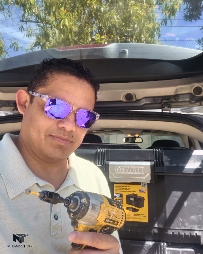 Man wearing purple sunglasses holding a DeWalt power drill in a car with an open trunk